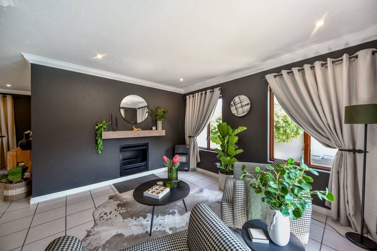 A cozy living room featuring dark accent walls, a built-in fireplace with a wooden mantelpiece, tiled flooring, and crown molding.