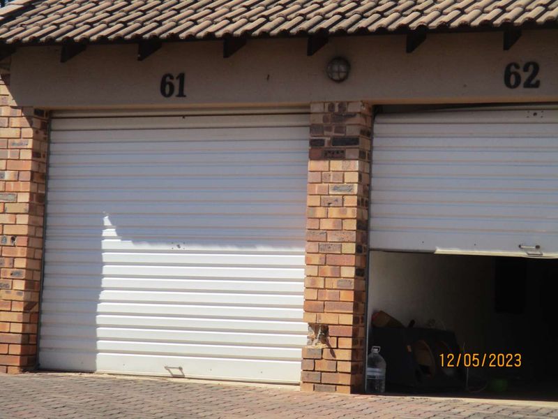 Exterior view of two garage units featuring roller shutter doors and face brick construction.