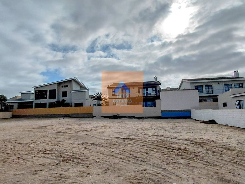 A vacant residential plot of land featuring sandy ground and surrounding boundary walls, situated in a developed neighborhood.