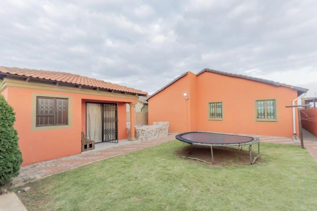 Rear view of the property featuring a paved patio area, built-in braai, and a small garden space.