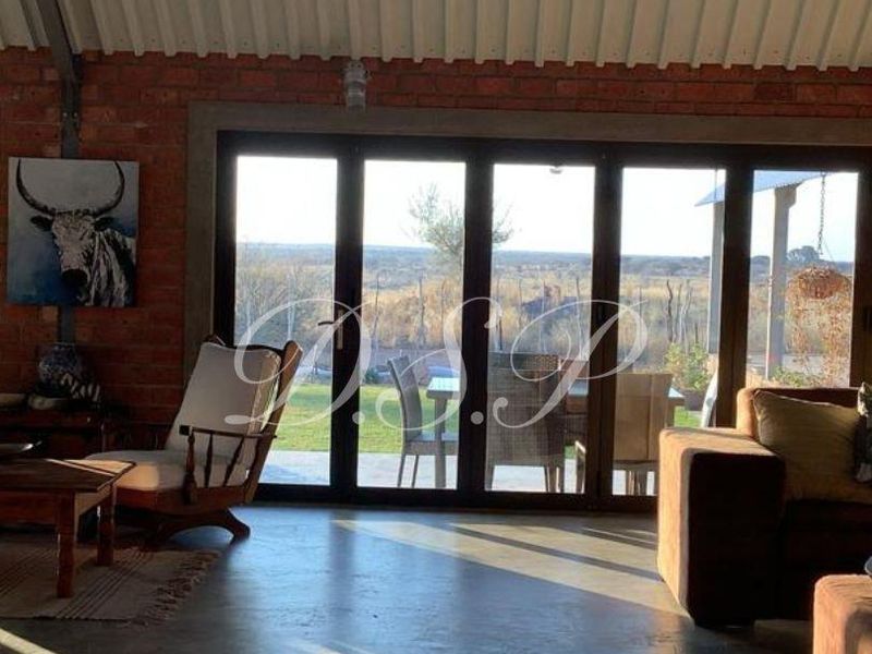 Spacious living area featuring exposed brick walls, polished concrete floors, and large folding glass doors that open to a scenic outdoor view.