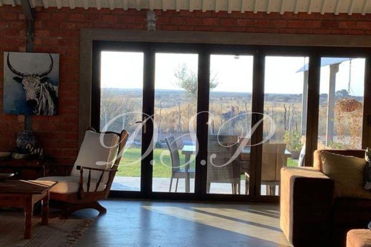 Spacious living area featuring exposed brick walls, polished concrete floors, and large folding glass doors that open to a scenic outdoor view.
