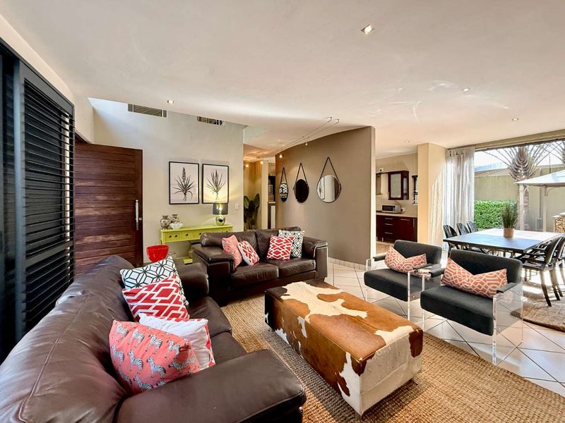 Spacious open-plan living and dining area featuring tiled floors, recessed lighting, and seamless flow to the outdoor patio through large sliding glass doors.
