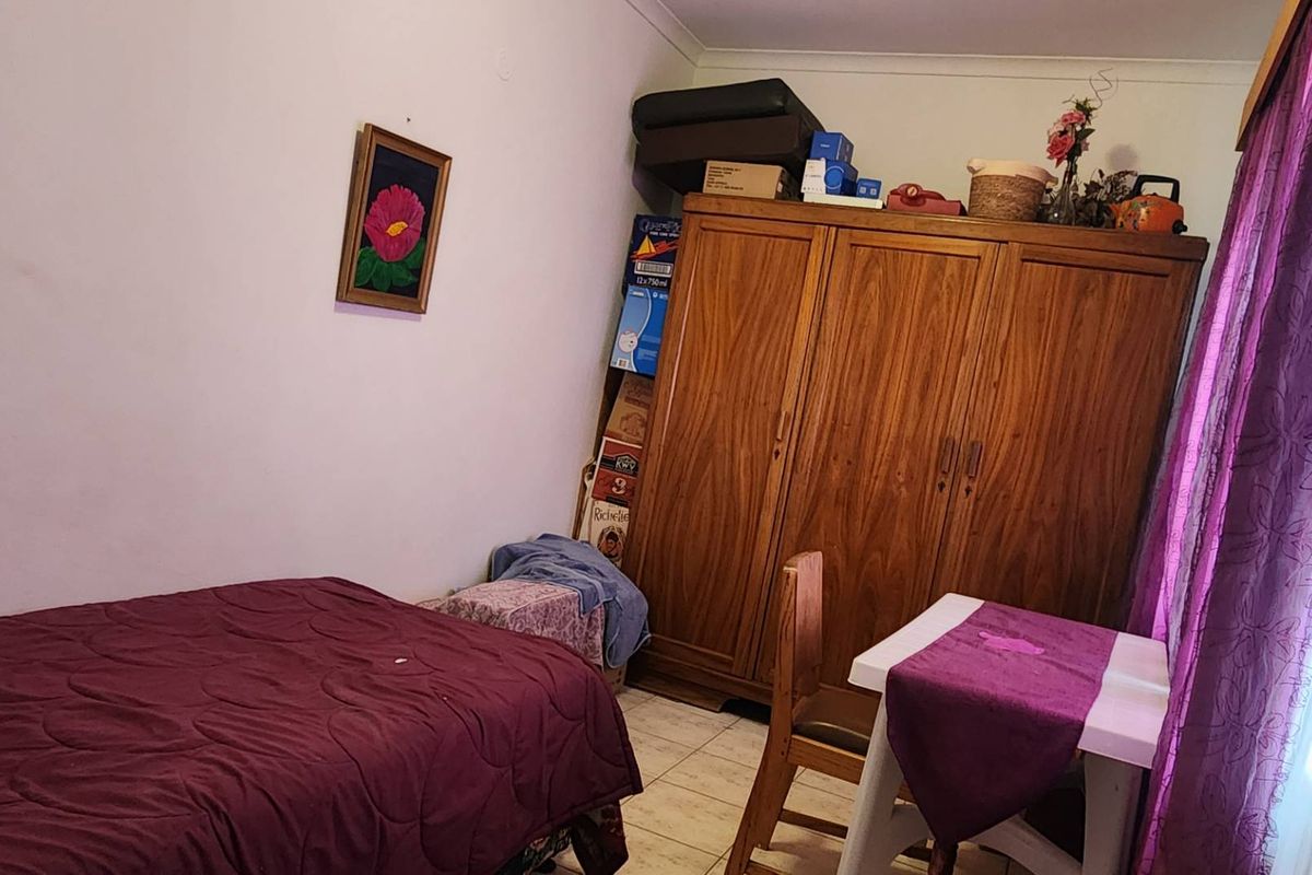 A bedroom featuring tiled flooring and a built-in wooden wardrobe.