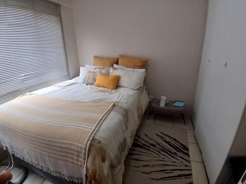 A functional bedroom featuring tiled flooring, a built-in wardrobe, and venetian blinds, providing a neutral base for personalization.