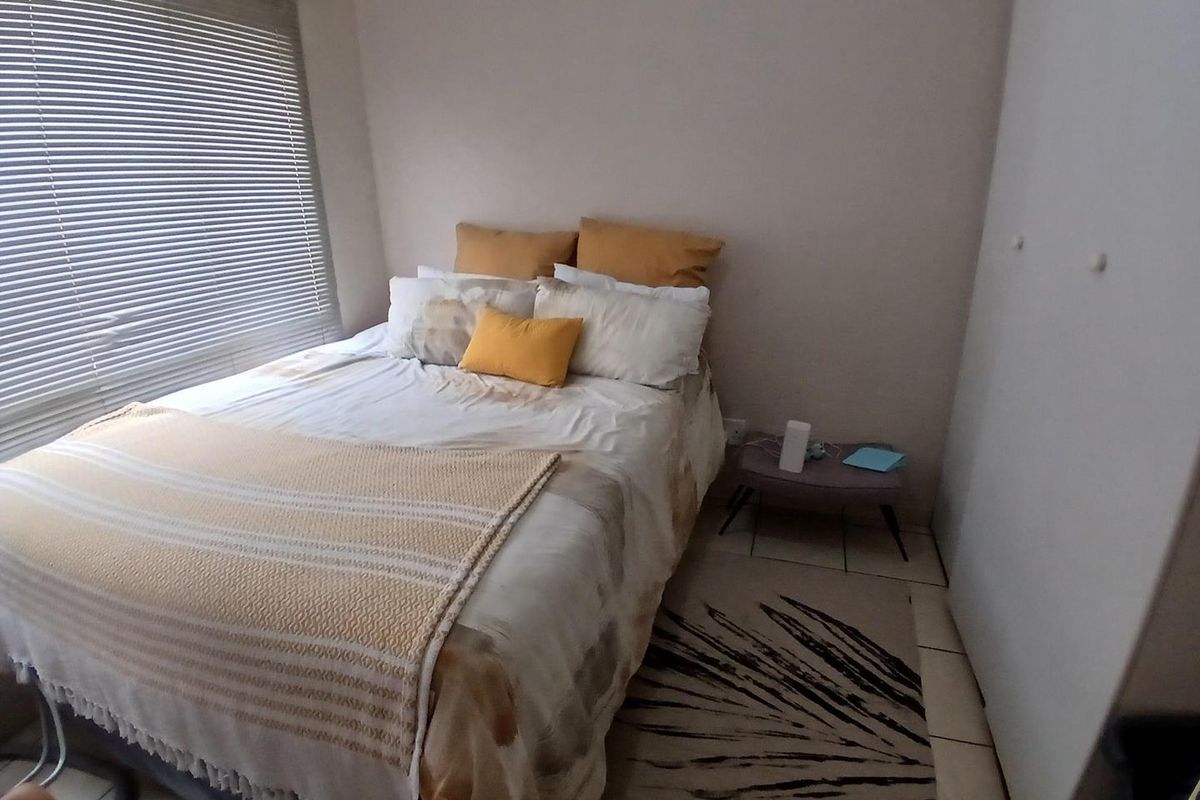 A functional bedroom featuring tiled flooring, a built-in wardrobe, and venetian blinds, providing a neutral base for personalization.