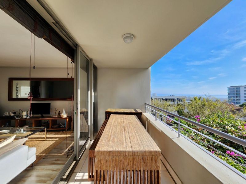 A covered balcony featuring tiled flooring, a metal safety railing, and sliding glass doors providing seamless access to the interior living space.