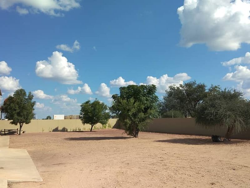 Spacious rear yard area featuring a corrugated metal industrial building, concrete apron, and secure perimeter wall with electric fencing.