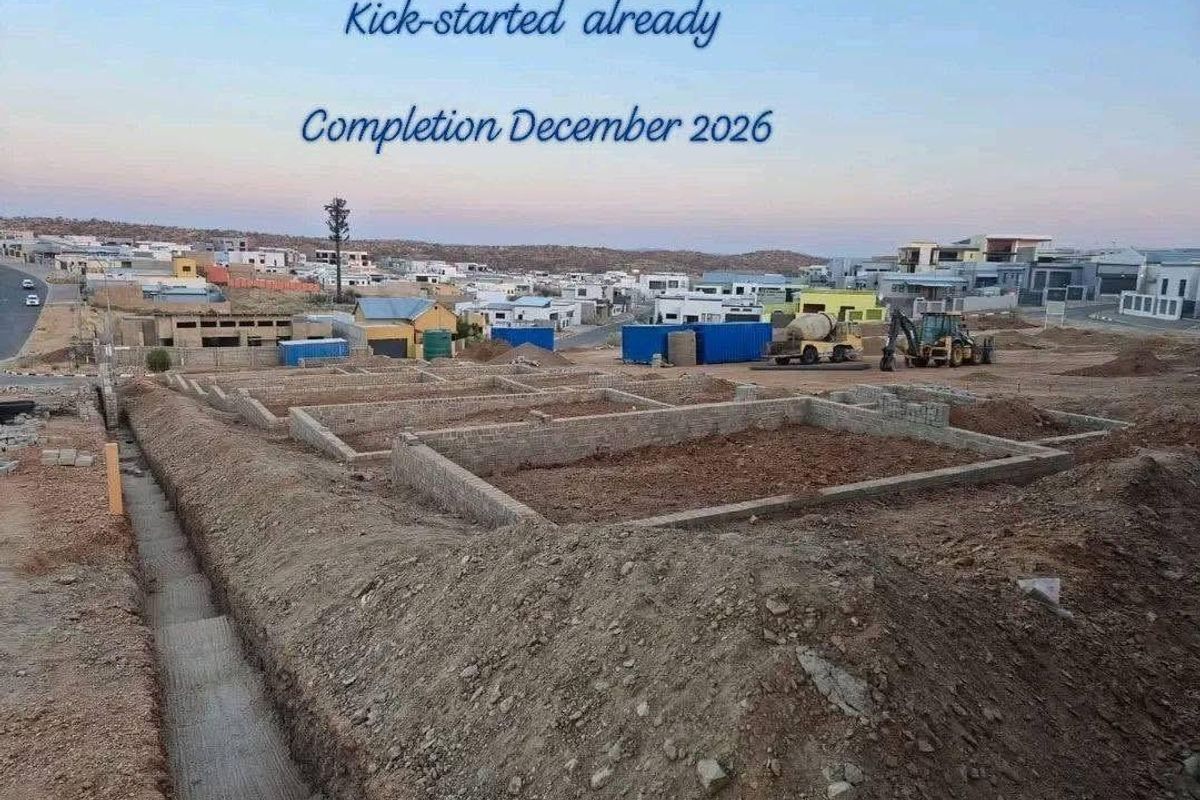 Construction site showing foundation work in progress for a new townhouse development, with completion scheduled for December 2026.