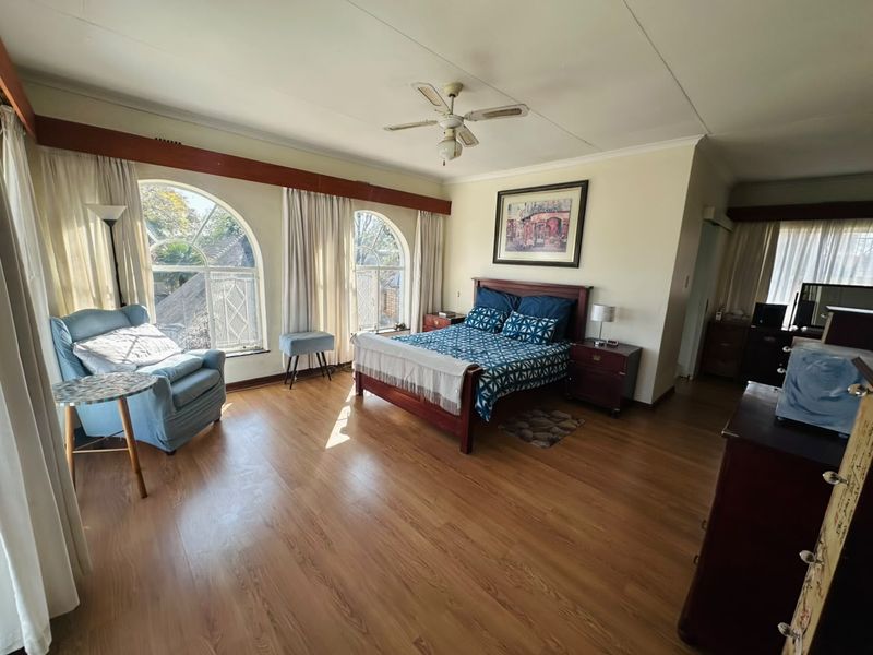 Spacious bedroom featuring laminate flooring, a ceiling fan, and distinctive arched windows that provide ample natural light.