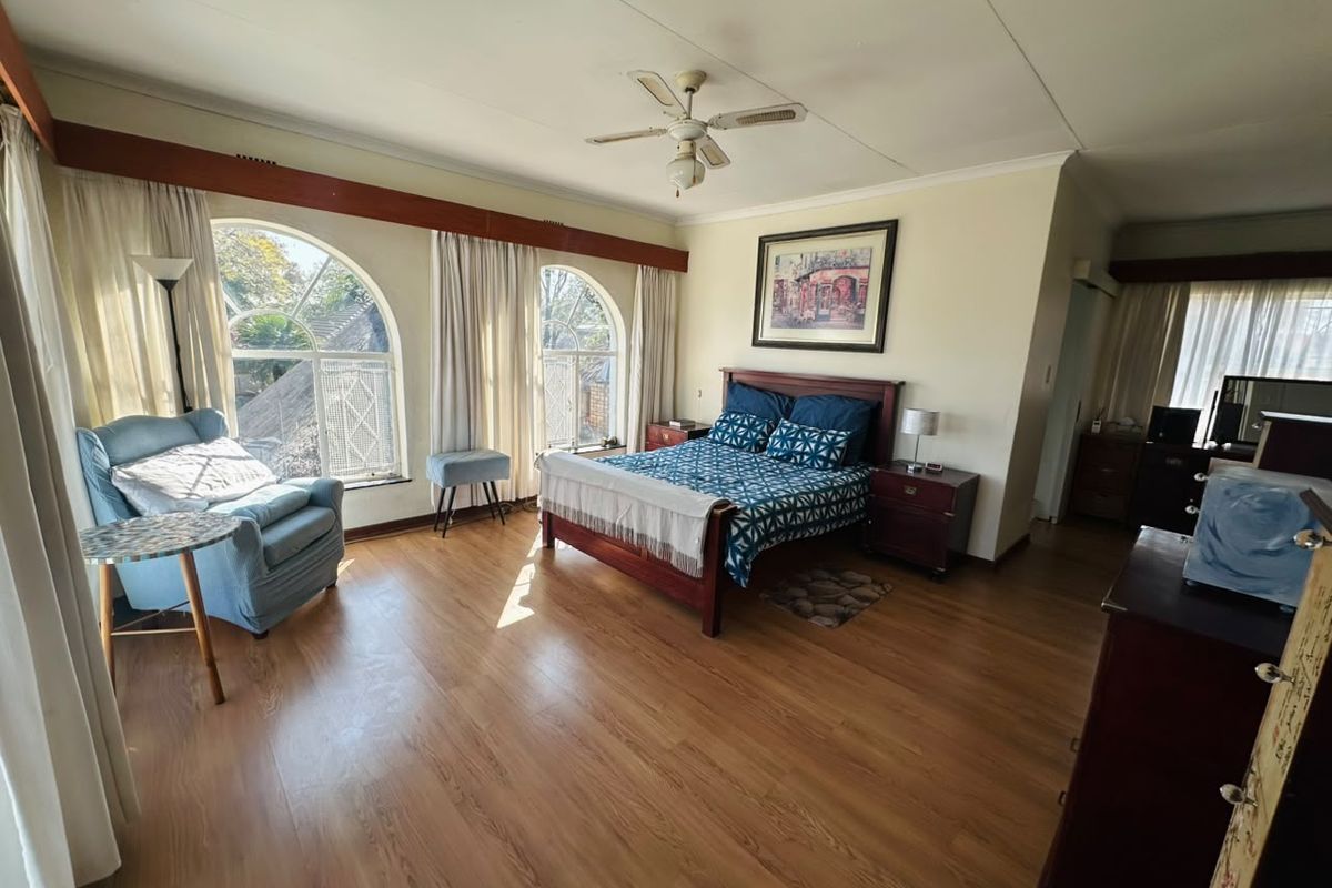 Spacious bedroom featuring laminate flooring, a ceiling fan, and distinctive arched windows that provide ample natural light.