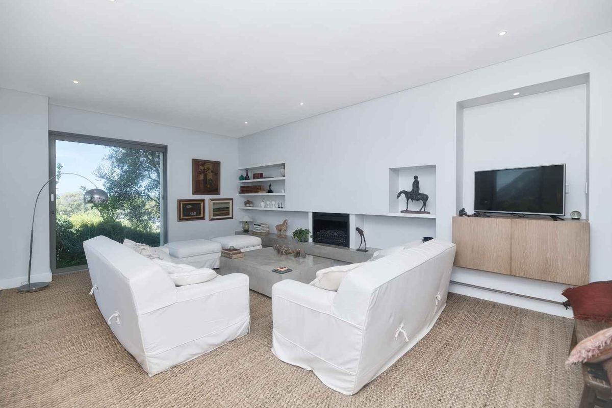A bright and modern living room featuring a built-in fireplace, recessed shelving, and large sliding glass doors providing natural light and garden views.