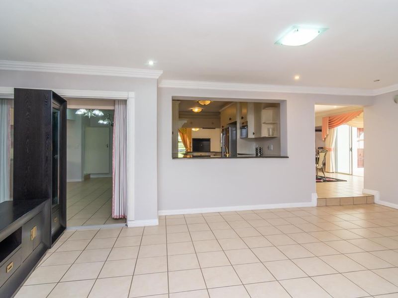 Spacious open plan living area featuring tiled flooring, recessed lighting, and a service window connecting to the kitchen area.