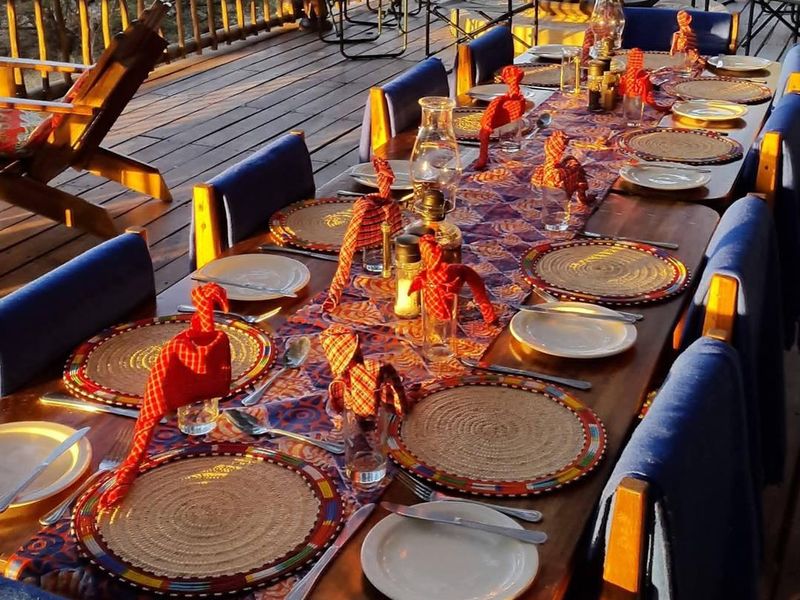 An outdoor timber deck patio area featuring a long dining table setup, overlooking the surrounding landscape.