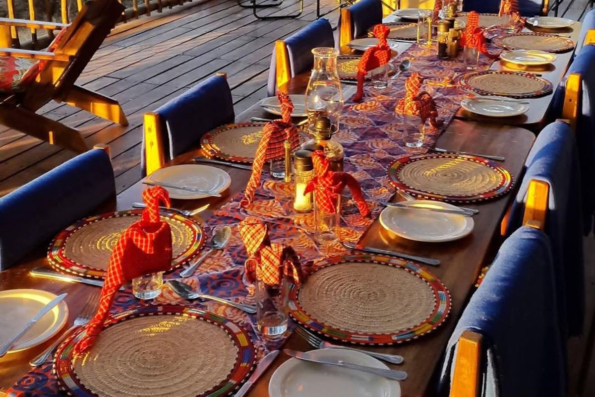 An outdoor timber deck patio area featuring a long dining table setup, overlooking the surrounding landscape.