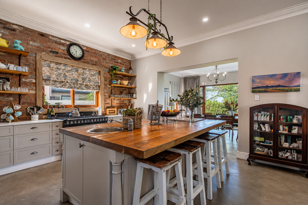 A well-appointed kitchen featuring an exposed brick wall, a large central island with a butcher block countertop, and high-quality finishes throughout.