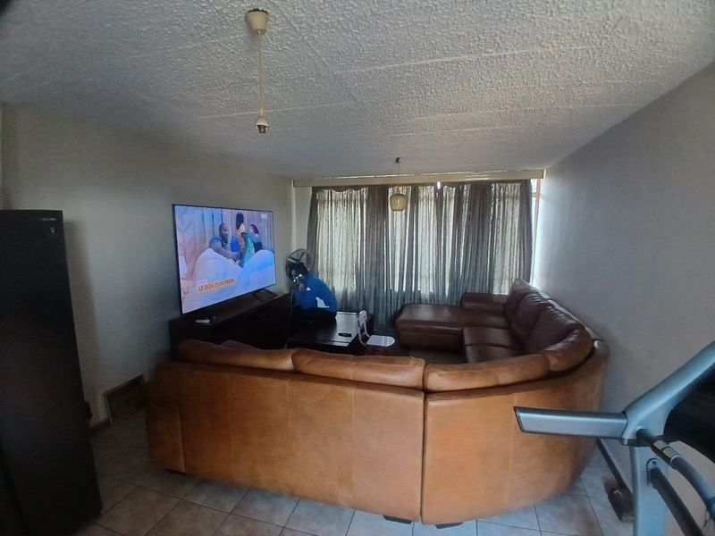 A living room area featuring tiled flooring and a textured ceiling, providing a functional space for relaxation.