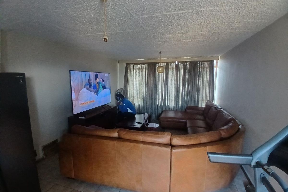 A living room area featuring tiled flooring and a textured ceiling, providing a functional space for relaxation.