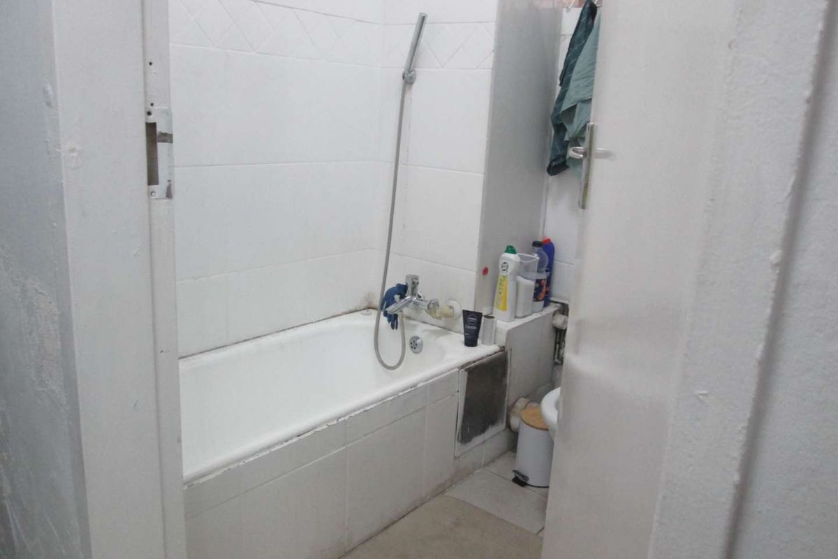 Compact bathroom featuring a built-in bathtub with a handheld shower mixer and tiled wall finishes.
