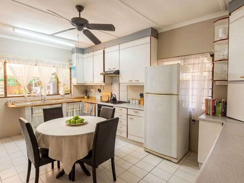 A functional kitchen featuring white cabinetry, tiled flooring, a ceiling fan, and a built-in hob with an extractor fan.