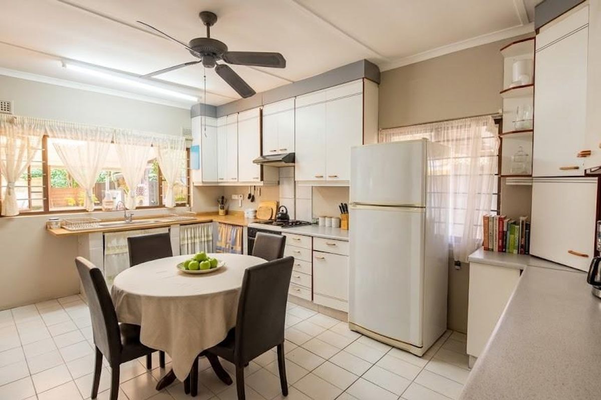 A functional kitchen featuring white cabinetry, tiled flooring, a ceiling fan, and a built-in hob with an extractor fan.