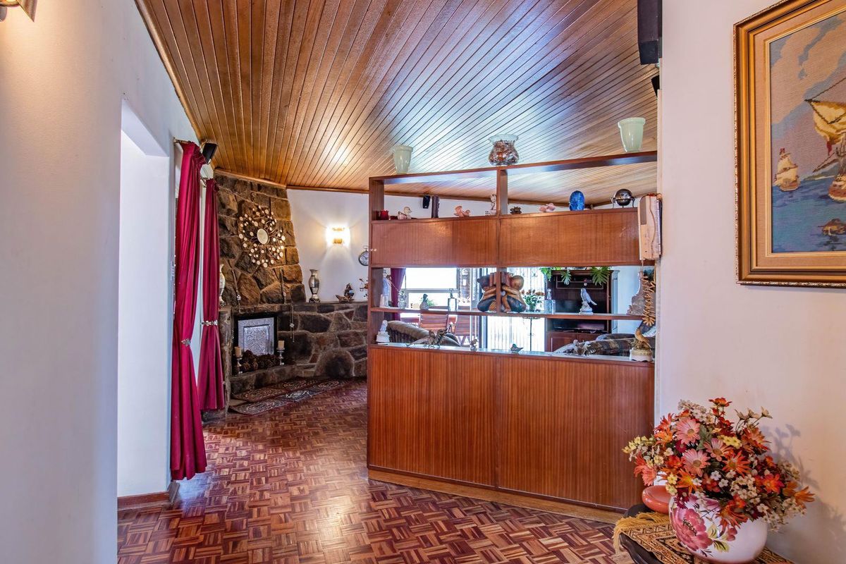 Living area featuring a stone fireplace, timber-clad ceiling, and a built-in wooden room divider, showcasing a traditional design aesthetic.