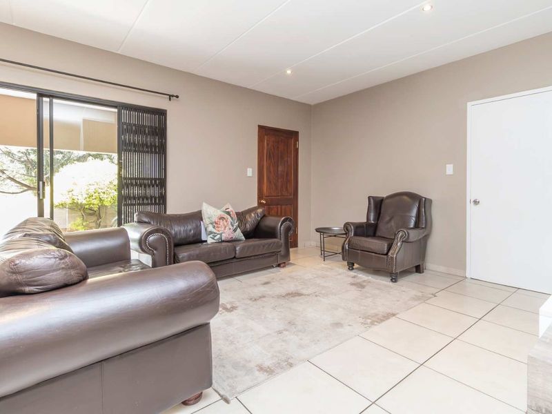 A bright living room featuring neutral tiled flooring, recessed lighting, and a sliding glass door providing access to the outdoor area.