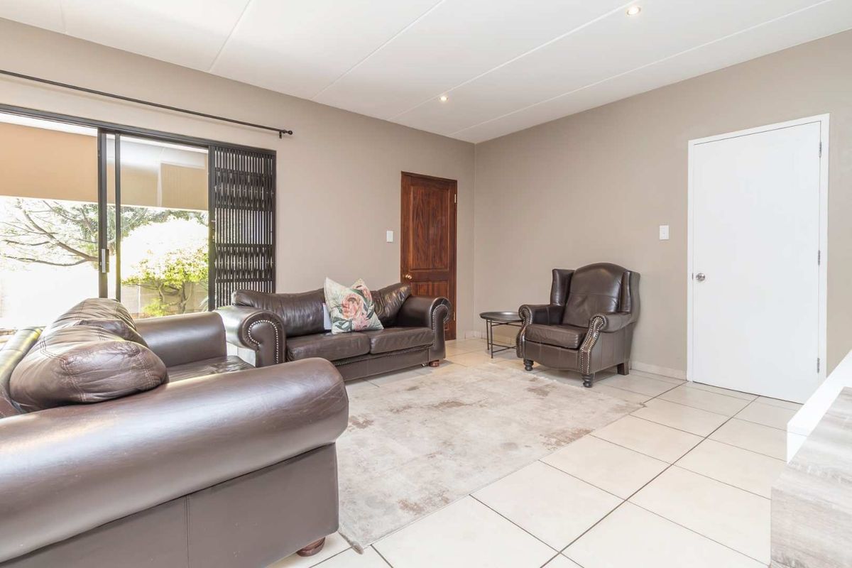 A bright living room featuring neutral tiled flooring, recessed lighting, and a sliding glass door providing access to the outdoor area.