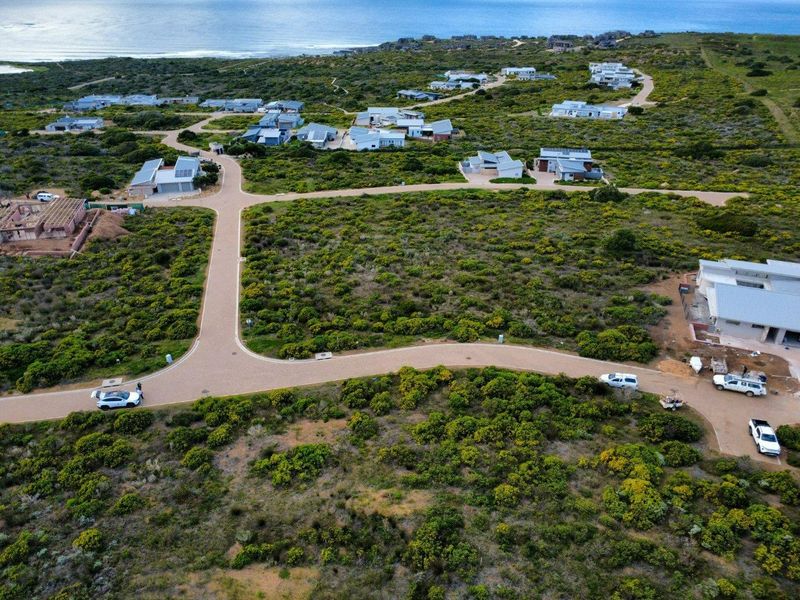 Aerial view of a residential estate development featuring paved roads and coastal landscape surroundings.
