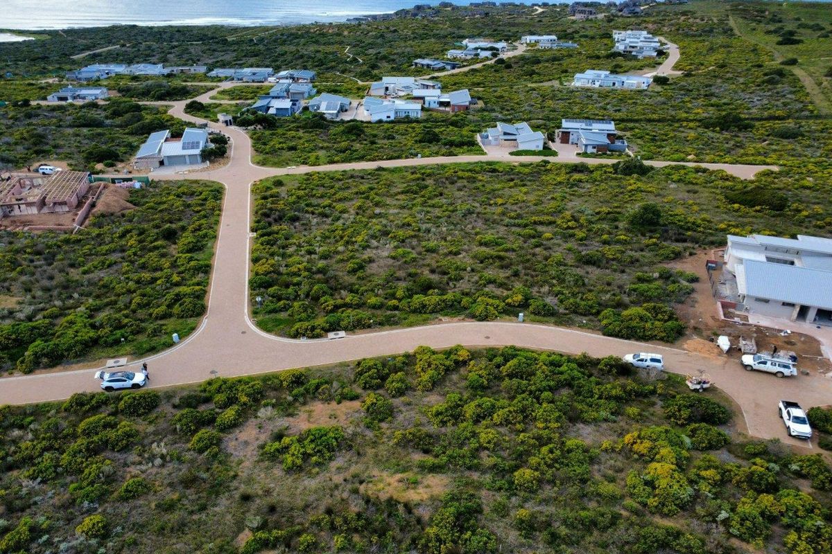 Aerial view of a residential estate development featuring paved roads and coastal landscape surroundings.