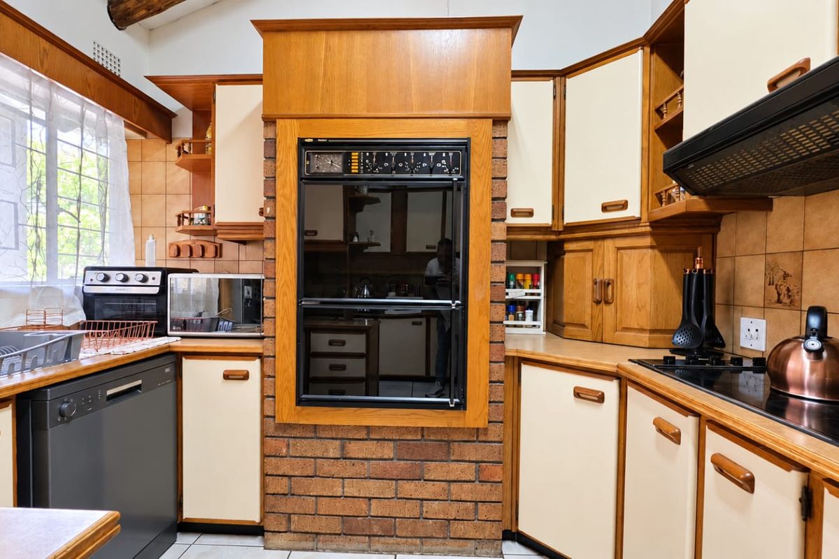 A traditional kitchen featuring wooden cabinetry, a built-in oven set into a brick feature wall, and tiled backsplash with ample counter space.