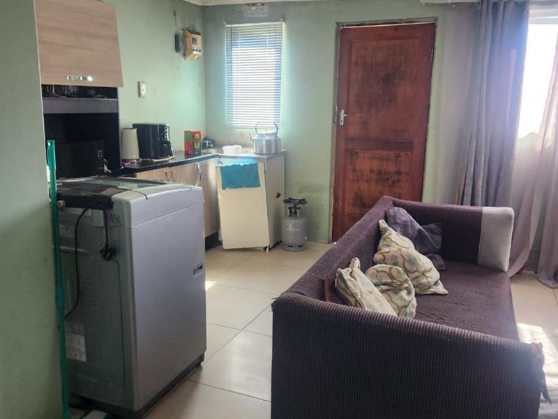 Open plan living and kitchen area featuring tiled flooring, built-in cabinetry, and ceiling panels, requiring cosmetic updates to improve the overall condition.