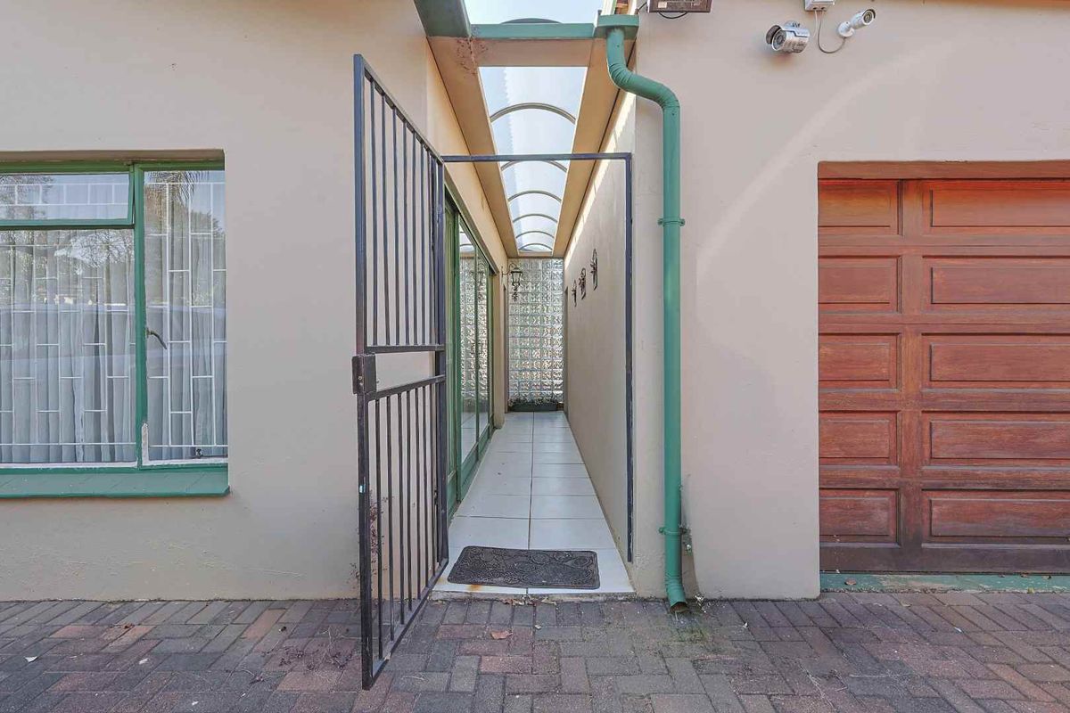 A covered side walkway featuring a translucent roof, glass block wall, and tiled flooring, providing access between the main structure and garage.