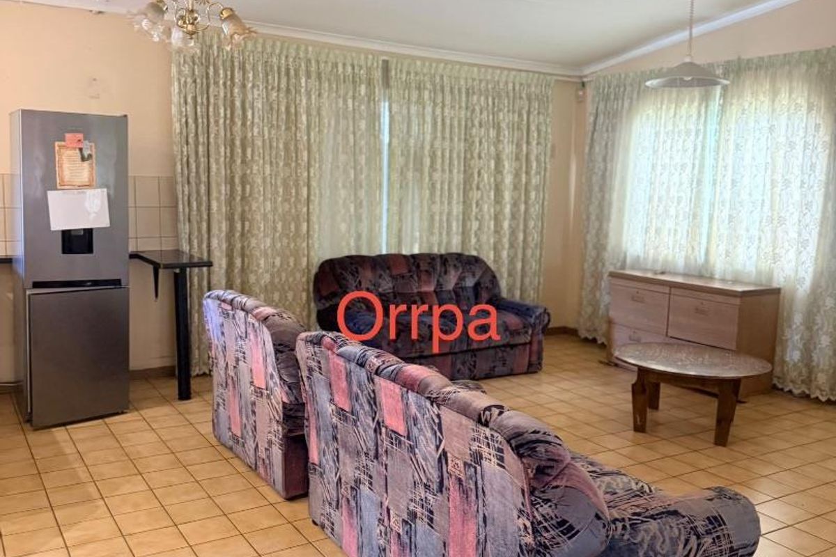 A spacious living area featuring tiled flooring, large windows with curtains, and integrated lighting, offering a functional layout for comfortable family living.