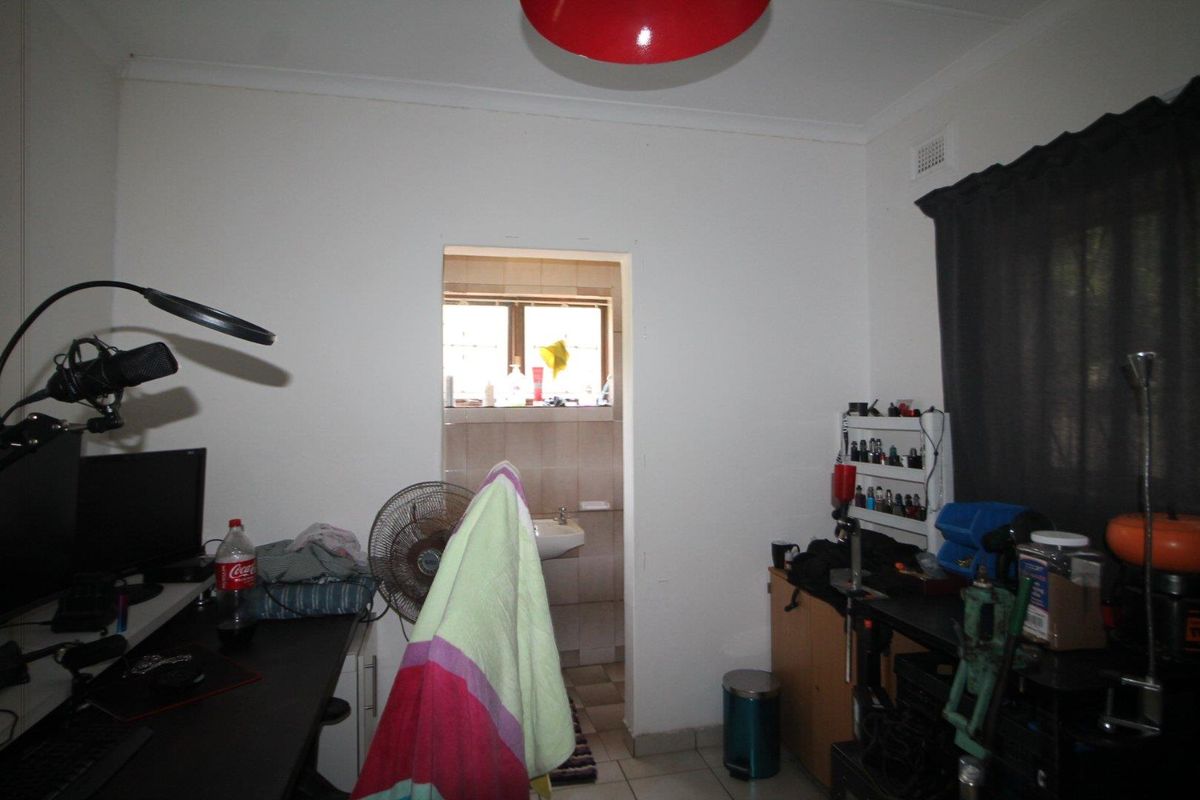 A bedroom space featuring a doorway leading to an en-suite bathroom with tiled walls and a basin.