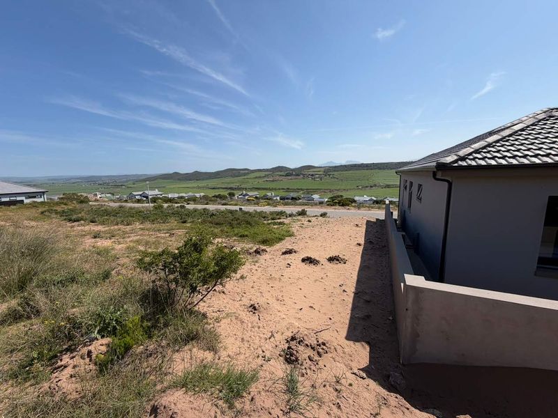 A view of the rear exterior of the property, showcasing the vacant land and surrounding landscape.