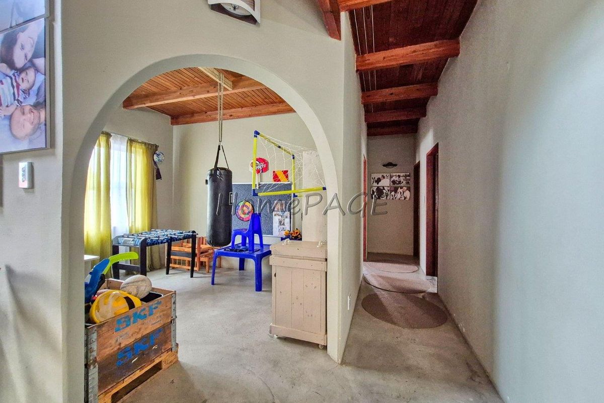 Living area featuring exposed timber ceiling beams and an arched entryway, providing a rustic architectural character to the space.
