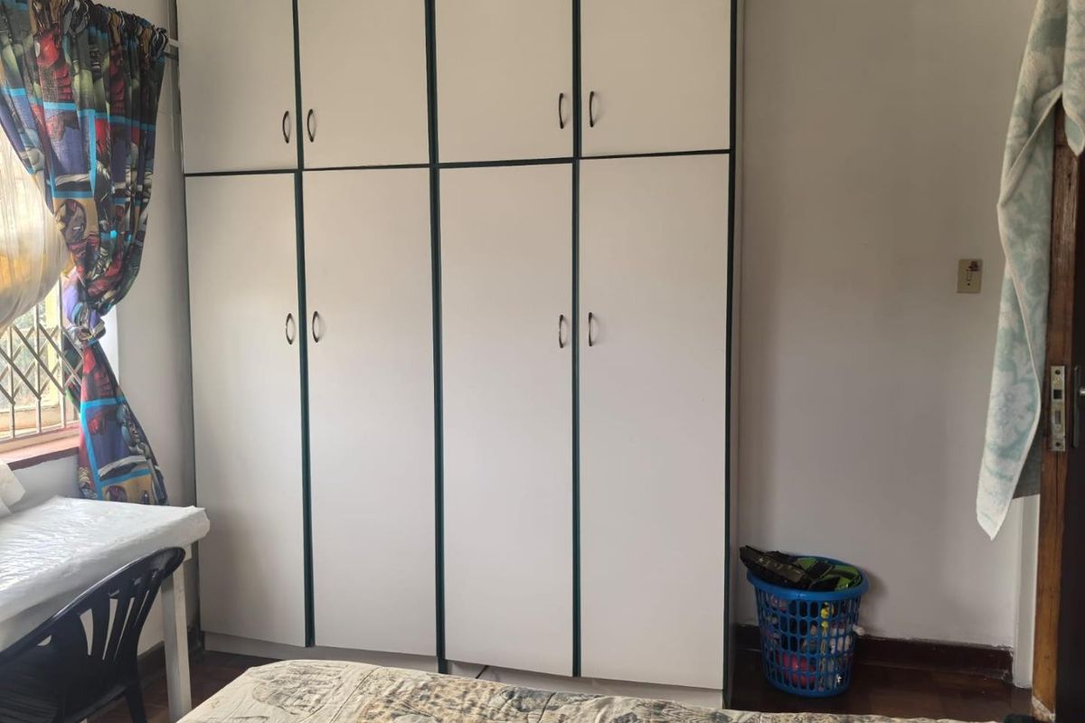 A bedroom featuring floor-to-ceiling built-in cupboards and wooden flooring, providing functional storage space.