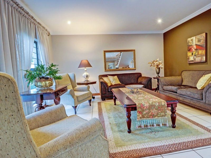 A comfortable living room featuring tiled flooring, recessed downlighting, and large windows with curtain tracks, offering a warm and inviting atmosphere.