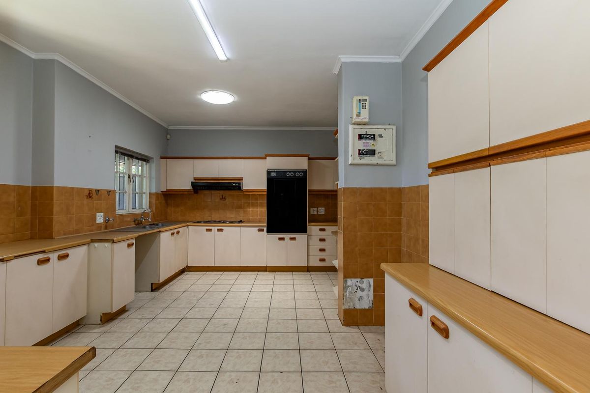 Spacious kitchen featuring built-in cabinetry, integrated oven, hob, extractor fan, and tiled flooring, offering a functional layout with ample storage space.