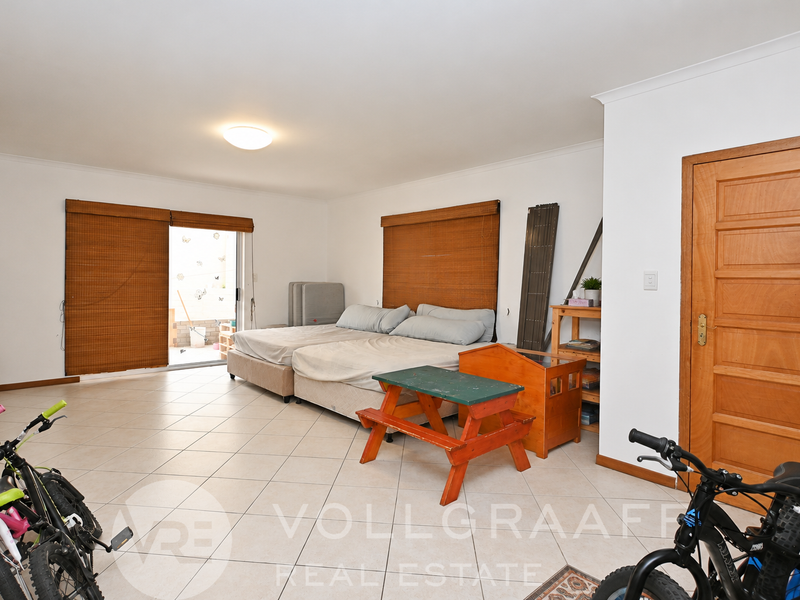 Spacious bedroom featuring tiled flooring, natural light through sliding glass doors, and direct access to an outdoor area.