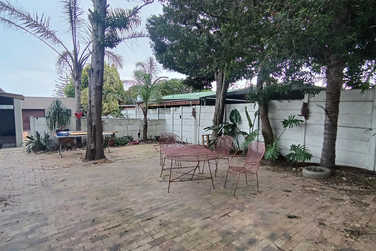 A spacious rear garden area featuring paved patio flooring and a precast concrete boundary wall, offering potential for landscaping and outdoor entertainment development.