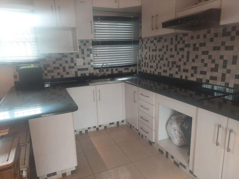 A functional kitchen featuring granite countertops, white cabinetry, tiled backsplash, and built-in extractor fan, offering a clean and practical workspace.