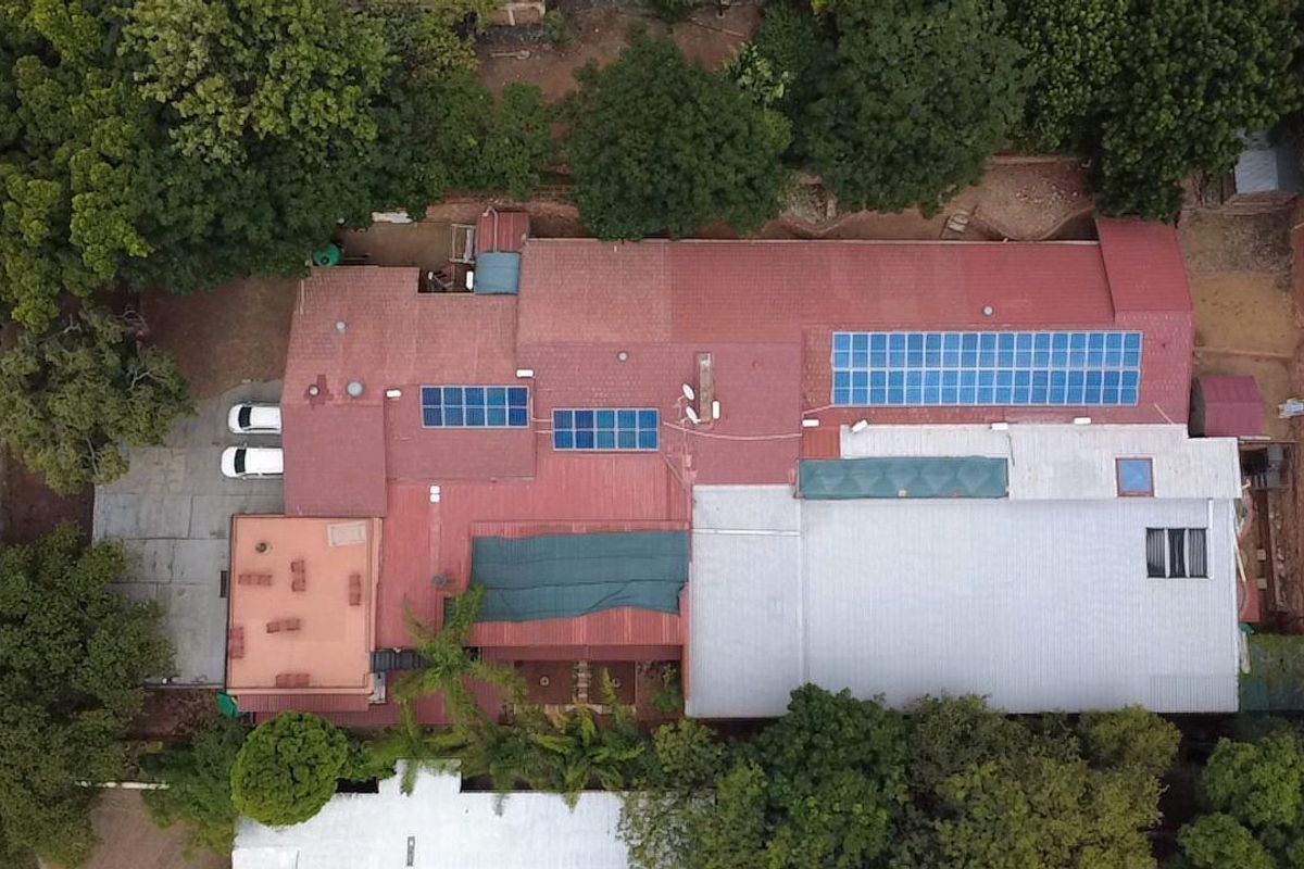 Aerial view of the property showing the extensive roof structure, integrated solar panel arrays, and surrounding landscaped grounds.