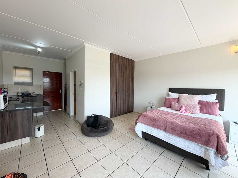 Open-plan studio apartment featuring a combined living and sleeping area with built-in cupboards and a functional kitchen with granite countertops.
