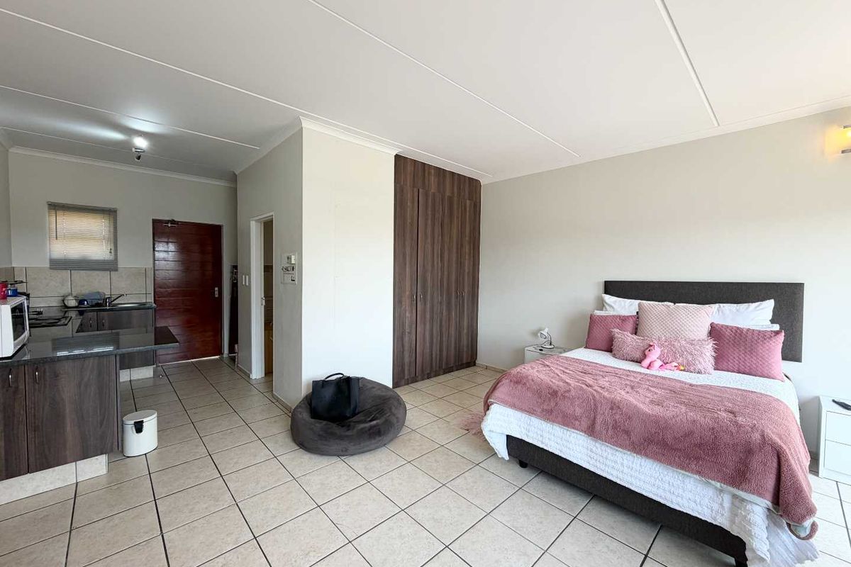 Open-plan studio apartment featuring a combined living and sleeping area with built-in cupboards and a functional kitchen with granite countertops.