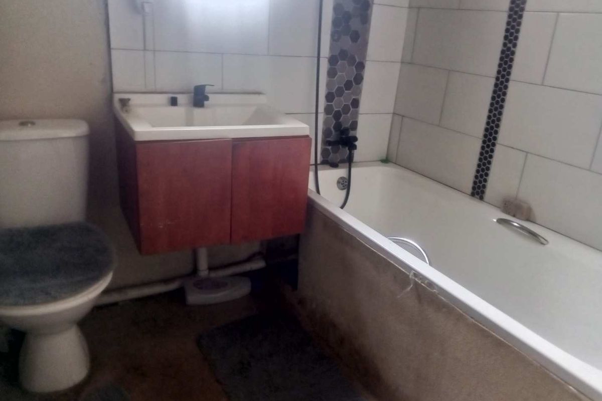 A compact bathroom featuring a bathtub with shower attachment, a wall-mounted vanity cabinet, and a standard toilet.