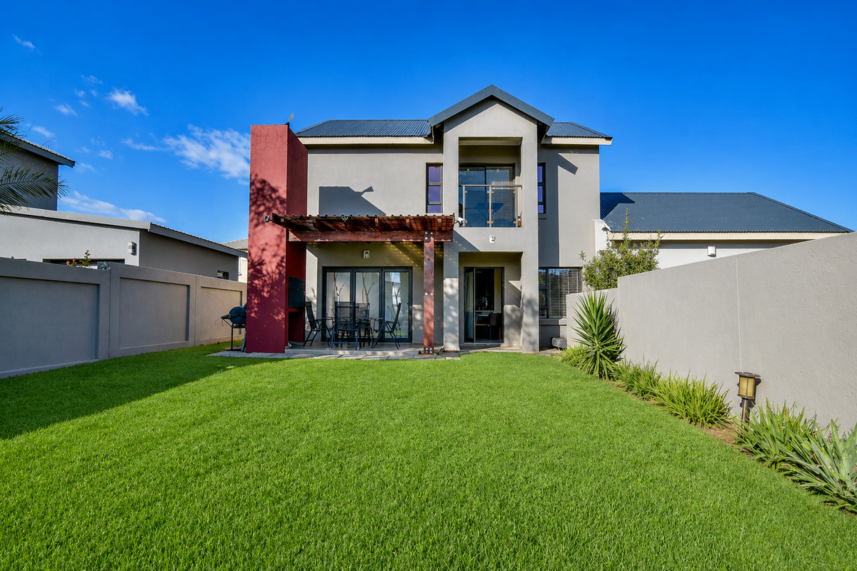 Rear view of a modern double-story house featuring a manicured lawn, a timber pergola, and a built-in braai area.