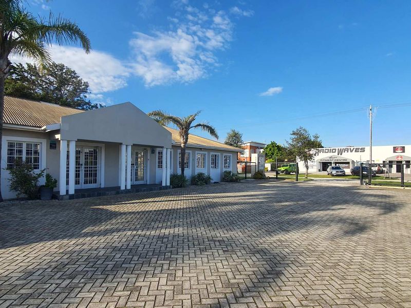 Front exterior view of the office building featuring a paved driveway, covered entrance porch with columns, and secure access points.