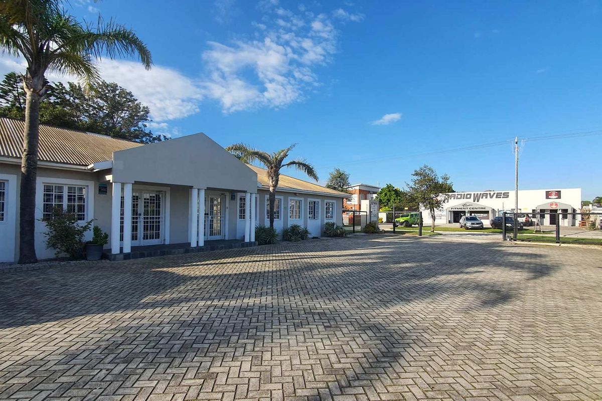 Front exterior view of the office building featuring a paved driveway, covered entrance porch with columns, and secure access points.